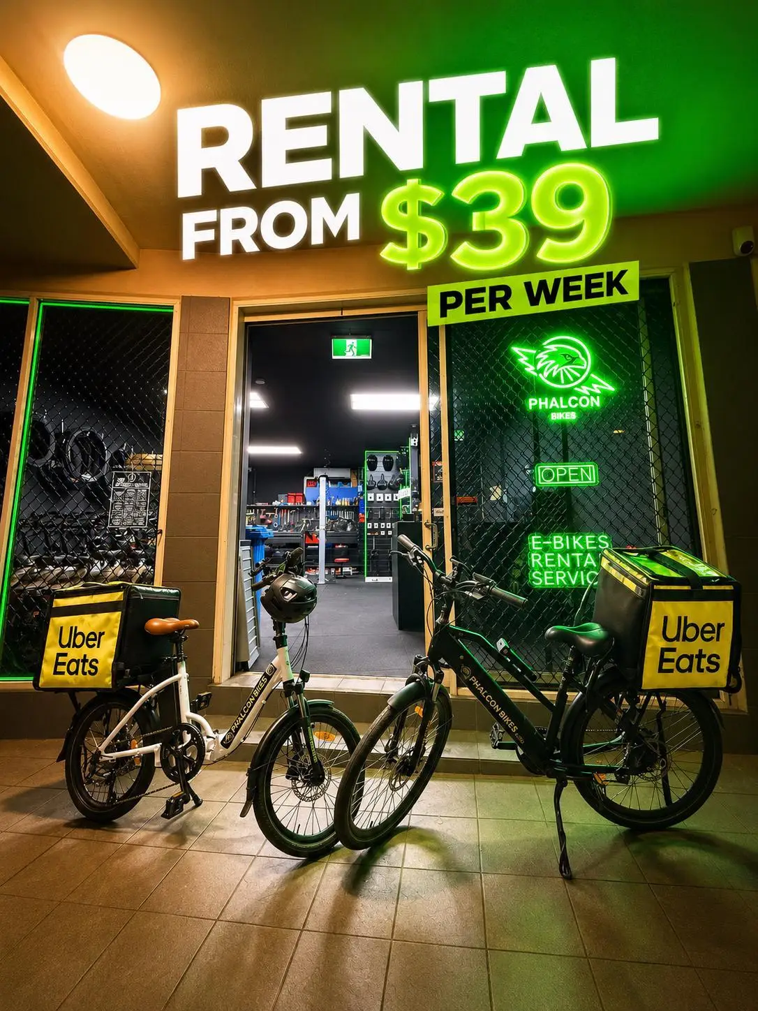 Two Phalcon rental e-bikes with delivery bags outside the lit Chippendale shopfront at night